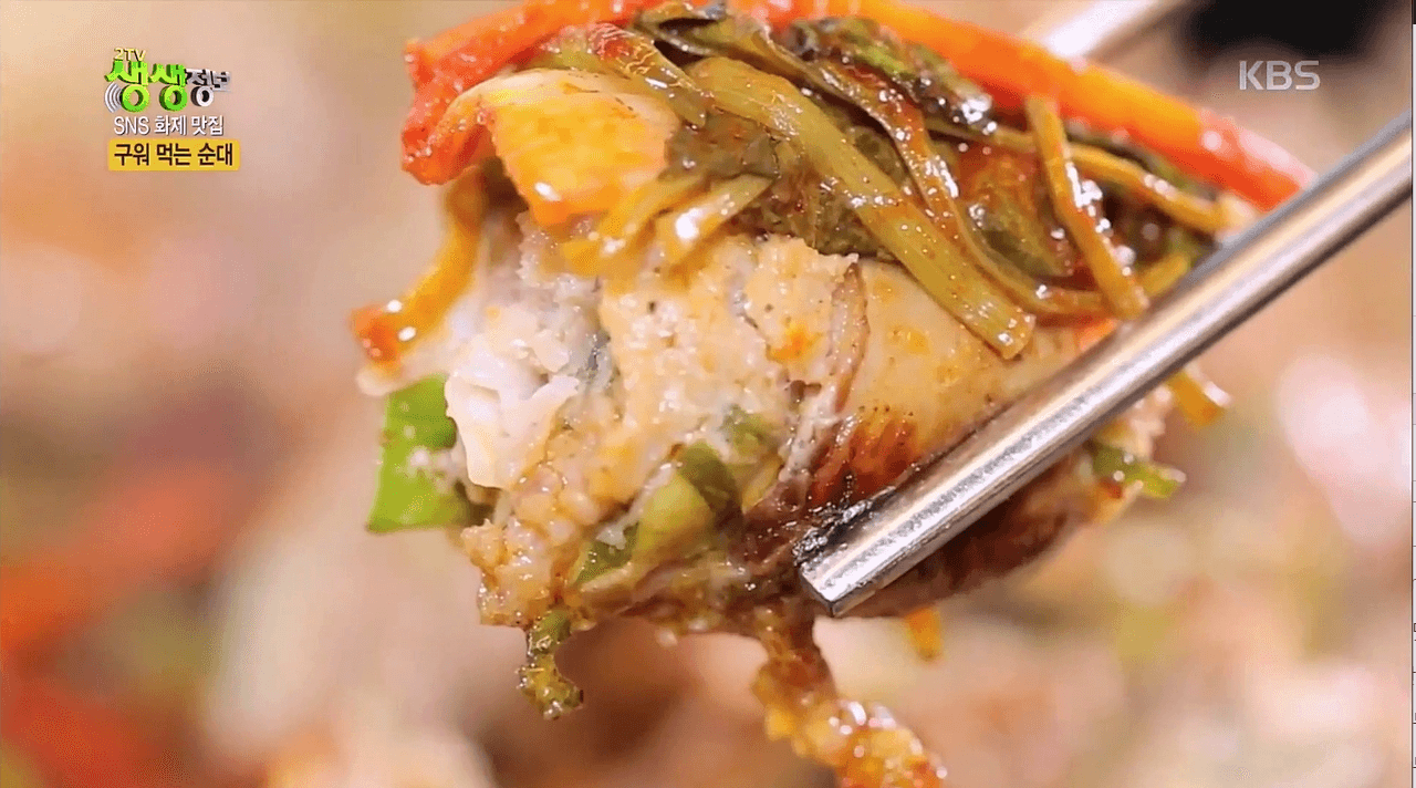 순대구이를 야채와 함께 젓가락으로 잡고 있는 사진 