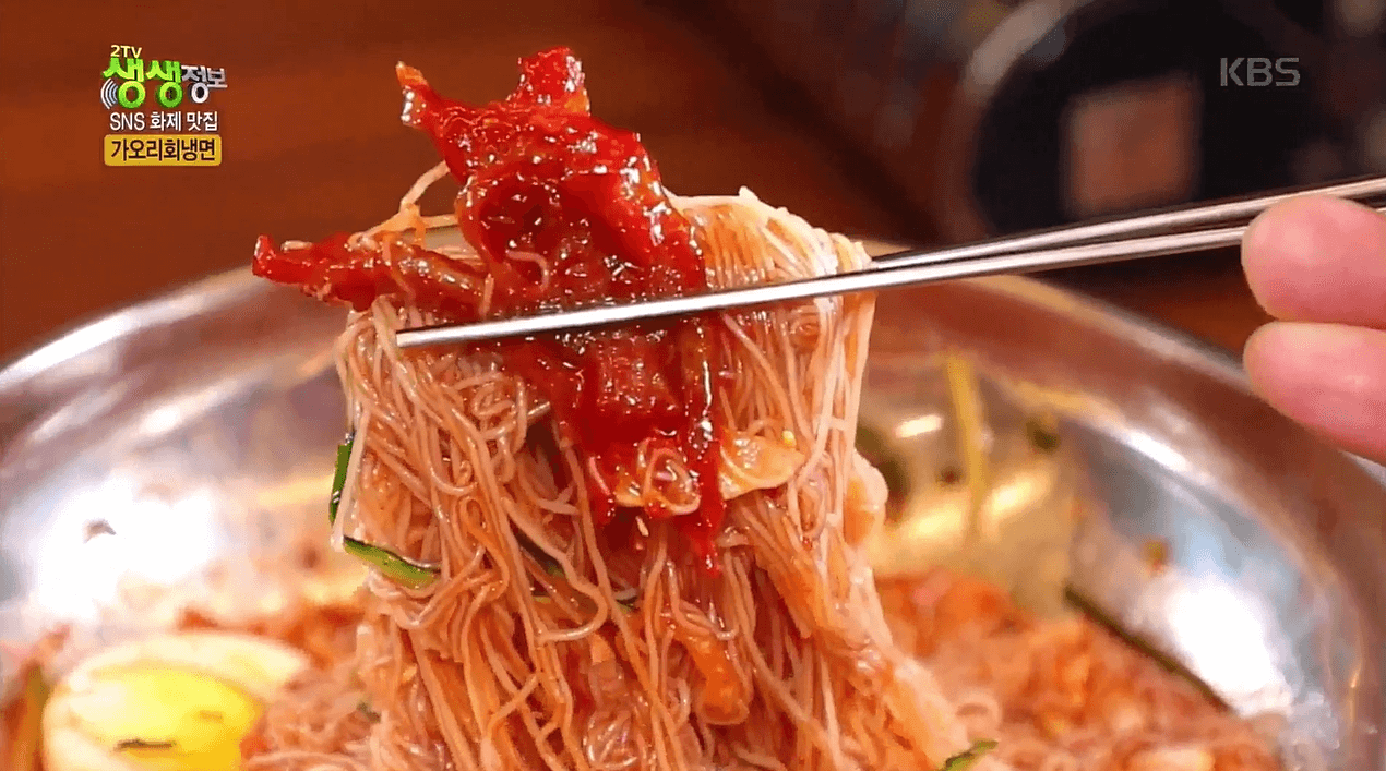 동해옥 함흥냉면을 가오리회와 함께 젓가락으로 들고 있는 사진 